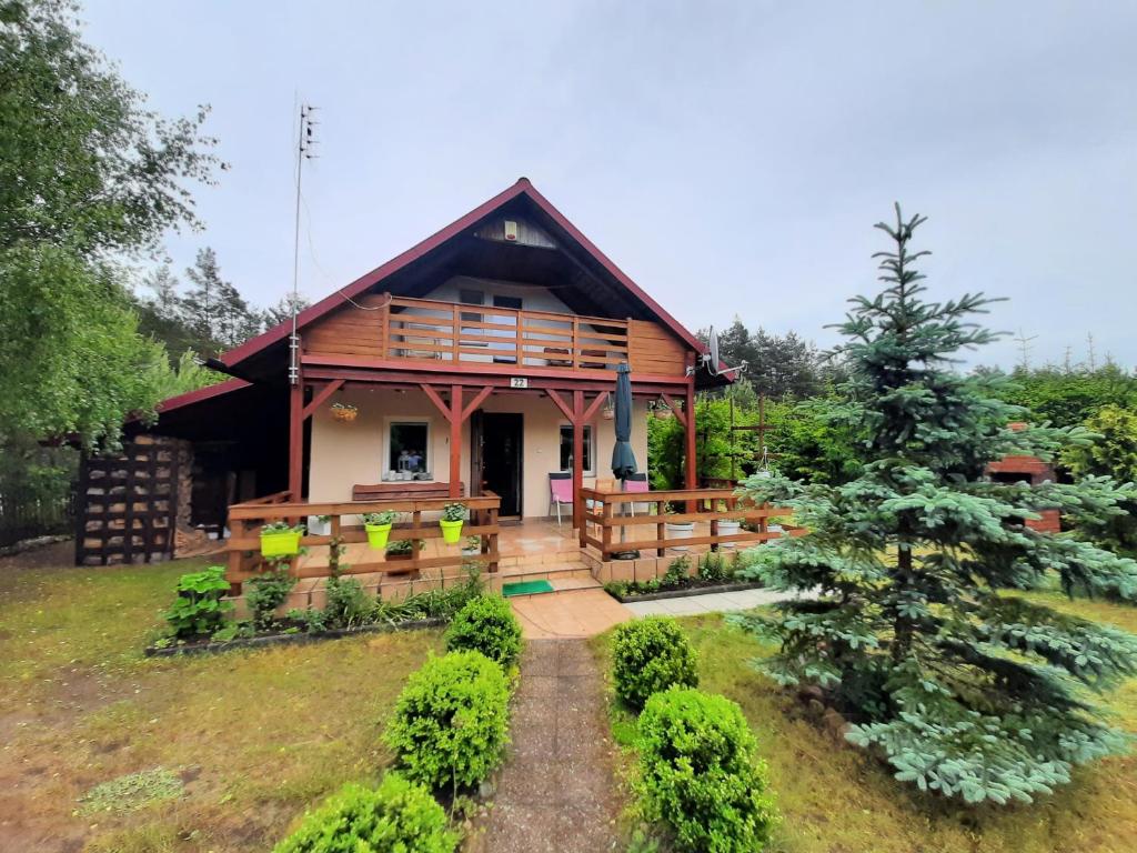 a house with a porch and a tree at Domek letniskowy Mały Mermet in Długie