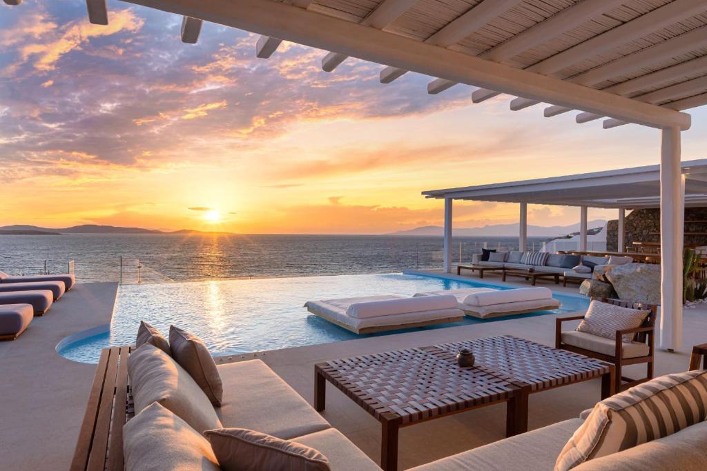 a villa with a swimming pool with a sunset at Villa Santa Esmeralda Mykonos in Agios Ioannis Mykonos