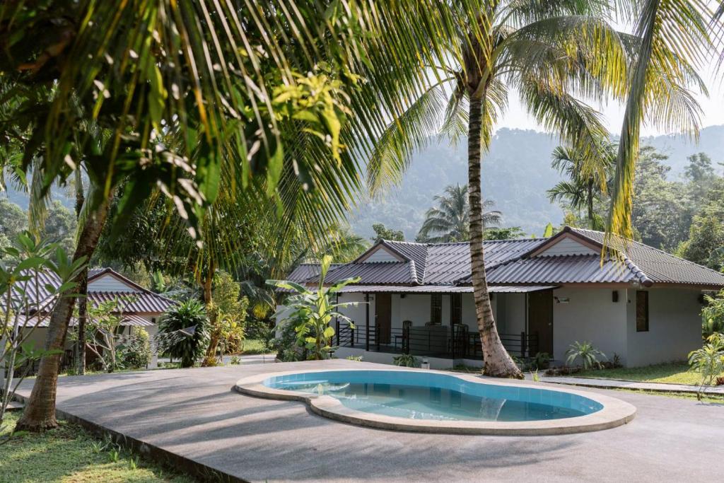 a house with a swimming pool and palm trees at Surfer's Village in Khao Lak