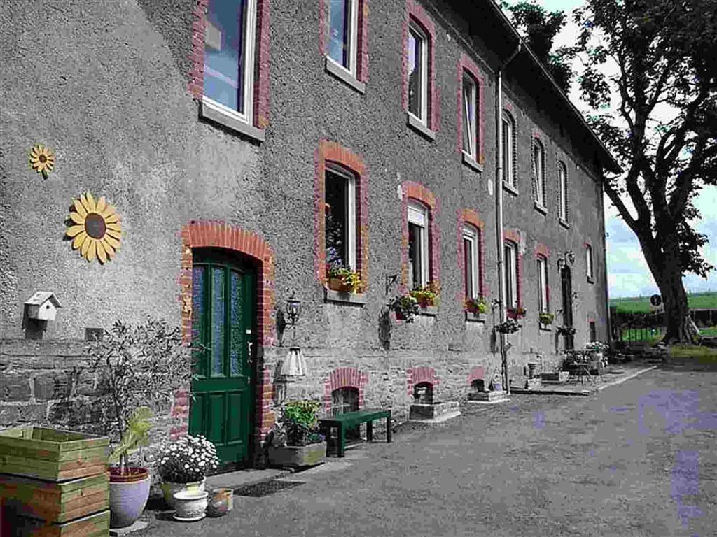 ein Gebäude mit einer grünen Tür und einer grünen Bank in der Unterkunft Holiday Home Weisten 5 in Burg-Reuland