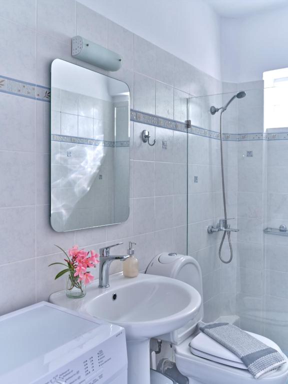 biała łazienka z umywalką i lustrem w obiekcie Ifestos home with private veranda, Paros w mieście Logaras