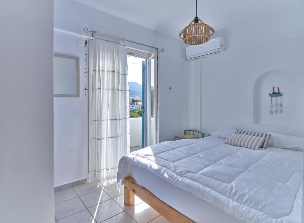 biała sypialnia z dużym łóżkiem i oknem w obiekcie Ifestos home with private veranda, Paros w mieście Logaras