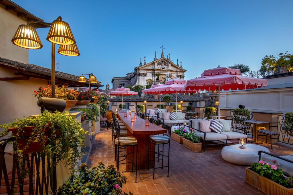 un patio al aire libre con mesas, sillas y sombrillas en 9Hotel Cesari en Roma