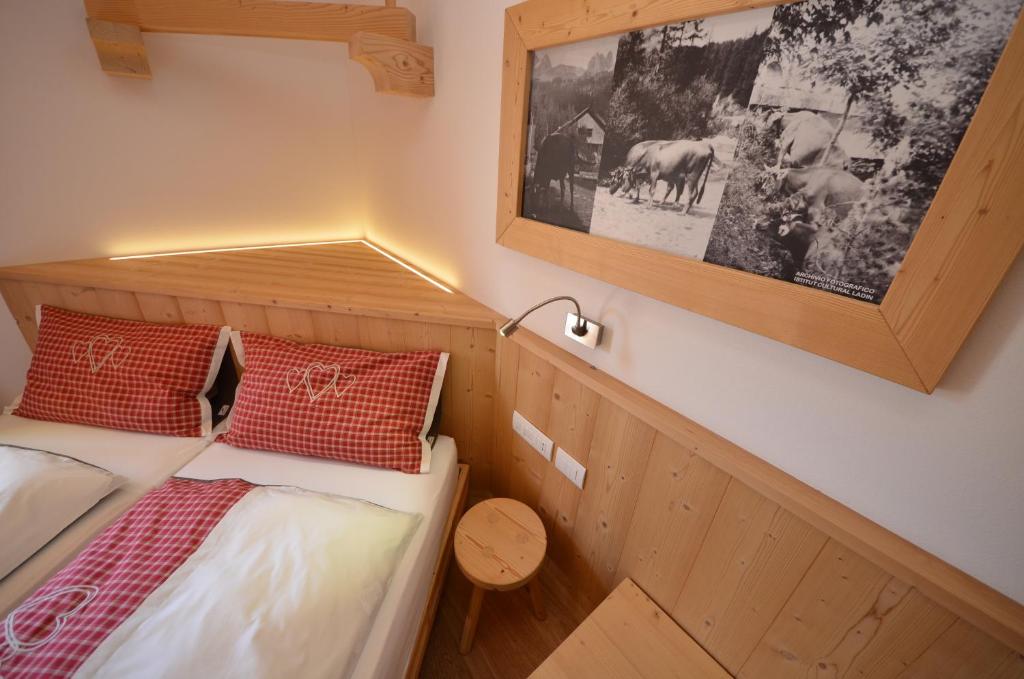 Habitación pequeña con cama y una foto en la pared en Agritur Majon da Mont, en Vigo di Fassa