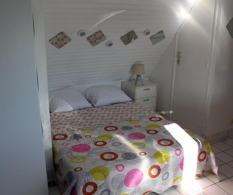 a bedroom with a bed with a colorful comforter at Le studio du dolmen à Plouharnel in Plouharnel