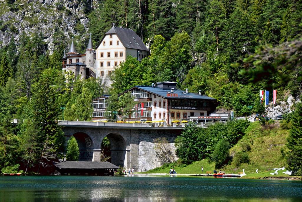 a bridge over a lake with a building on it at Hotel Schloss Fernsteinsee in Nassereith