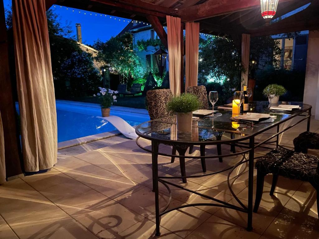 un patio con una mesa y una piscina por la noche en Bulles & Bubbles..., en Juvancourt