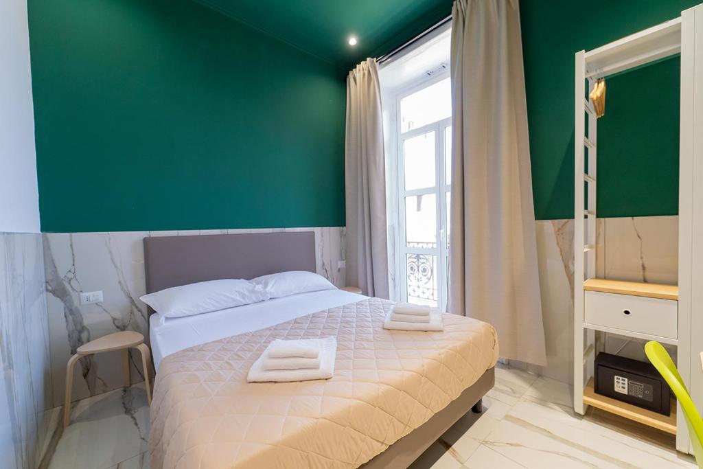 sypialnia z zieloną ścianą i łóżkiem z ręcznikami w obiekcie P.C. Boutique H. De Gasperi, Napoli Centro, by ClaPa Group w mieście Napoli