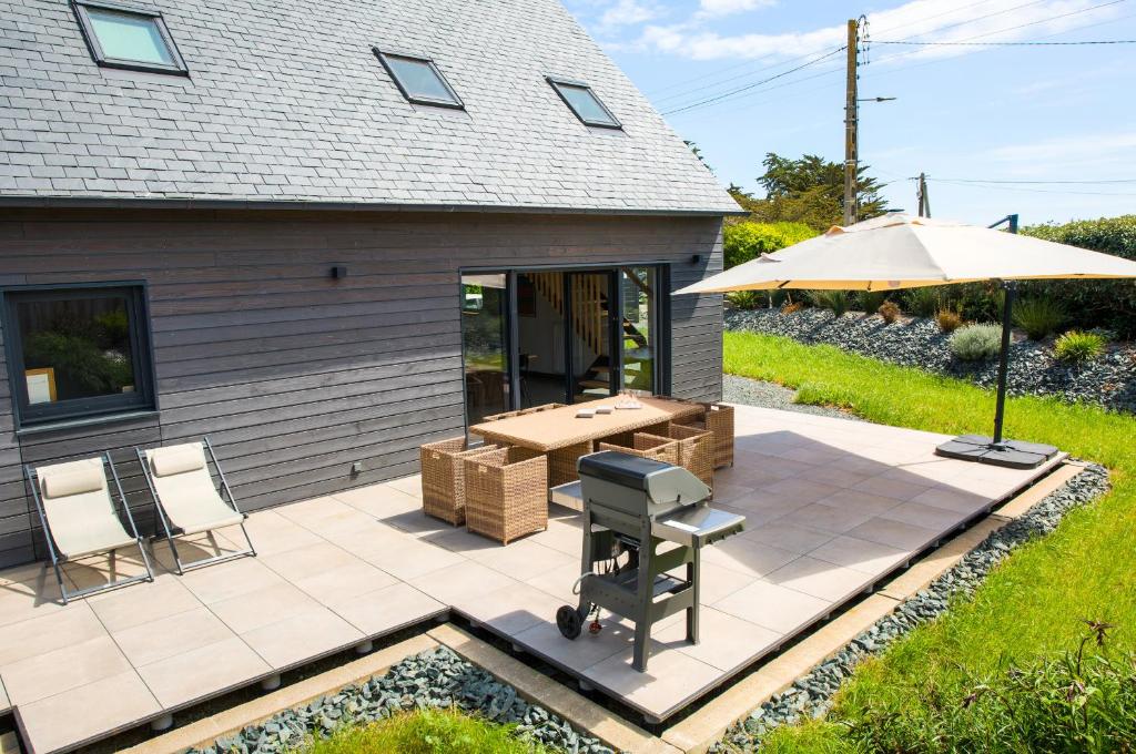 a patio with a table and an umbrella at Charmante maison pour 5 au coeur de Penmarch in Penmarch