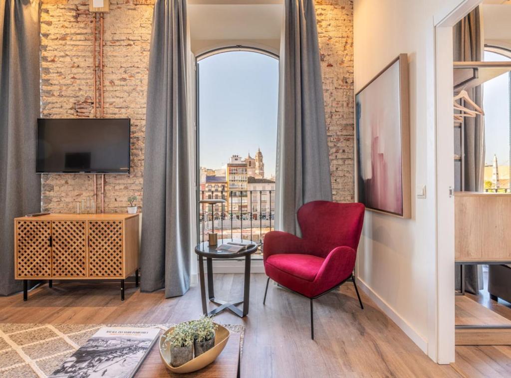 a living room with a red chair and a window at Home Art Apartments Málaga in Málaga