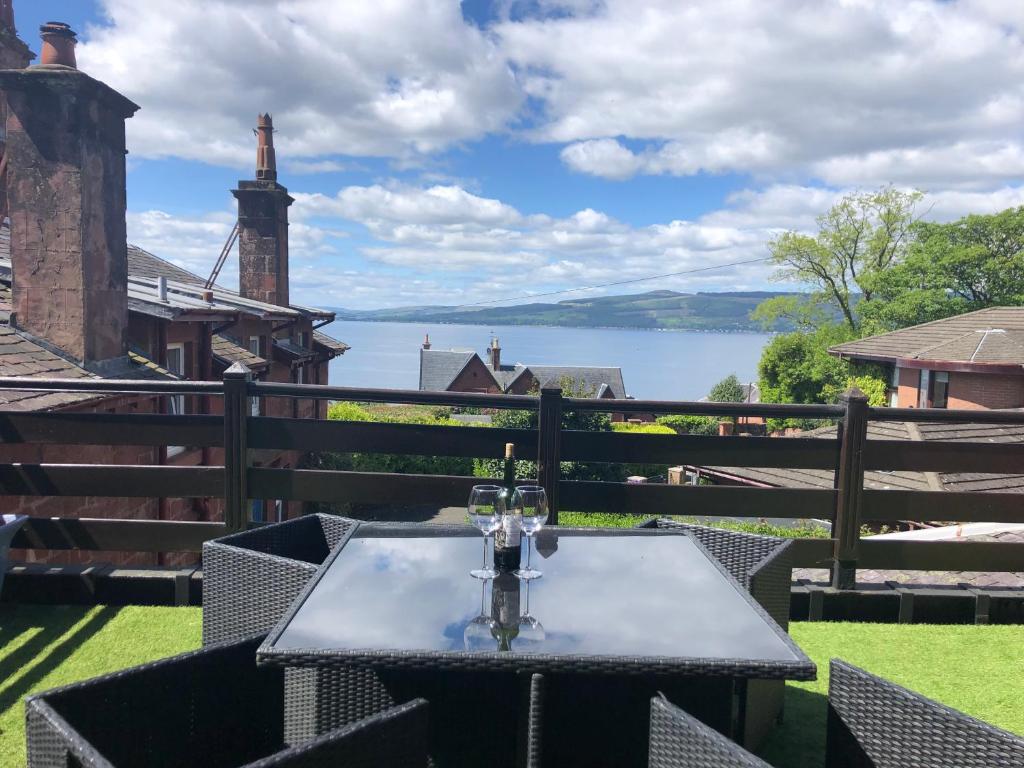 a table with wine glasses on a balcony with a view of a lake at The Coach House in Skelmorlie