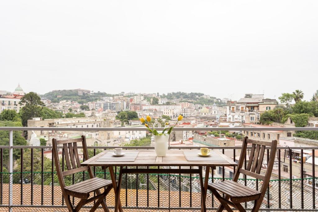 un tavolo con sedie e un vaso di fiori sul balcone di Panoramic Flat between Materdei and Fontanelle a Napoli