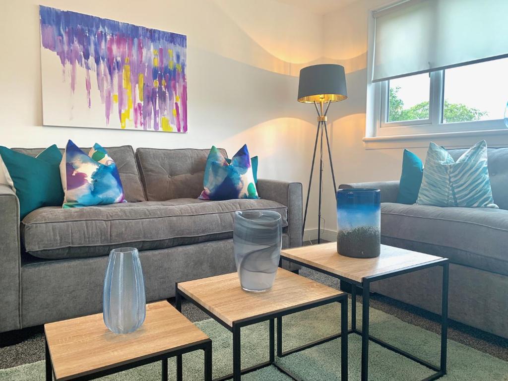 ein Wohnzimmer mit zwei Tischen mit Vasen darauf in der Unterkunft Waverley in East Kilbride