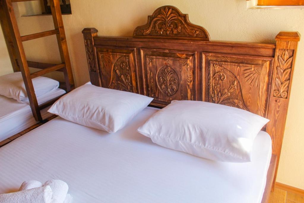 a bed with a wooden headboard and two white pillows at Silver Hill Guesthouse in Gjirokastër