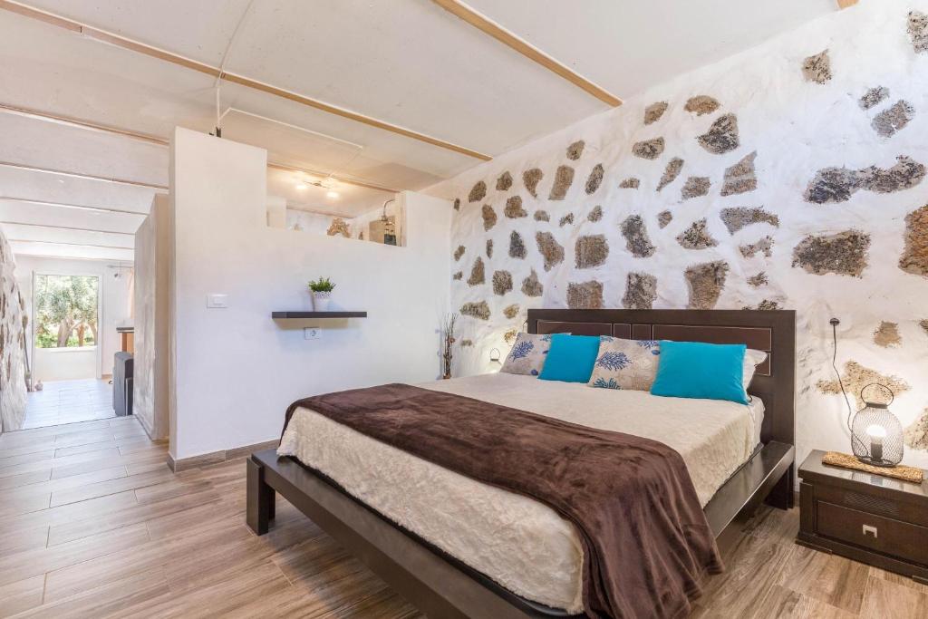 a bedroom with a bed and a stone wall at Edén Ecologico en Casa La Fuentita in El Charco