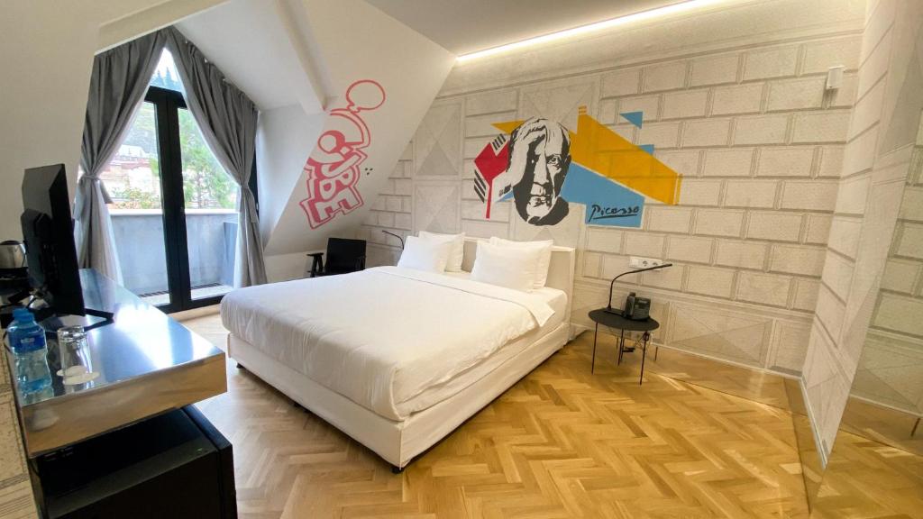sypialnia z białym łóżkiem i ścianą z graffiti w obiekcie Platforma Design Hotel w mieście Tbilisi City