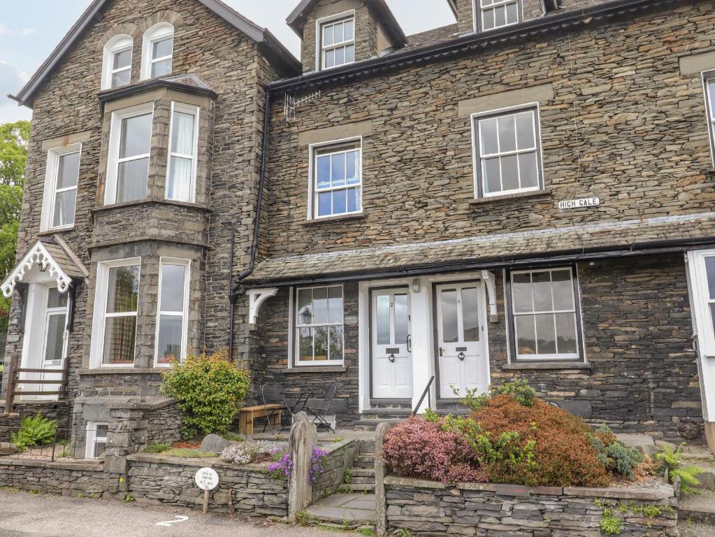 een oud stenen huis met witte deuren en ramen bij Primrose Cottage in Ambleside