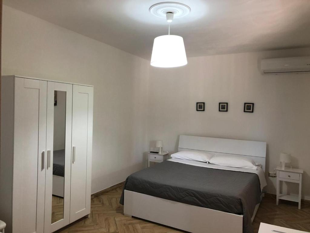a white bedroom with a bed and a lamp at Casa Giulia in Niscemi
