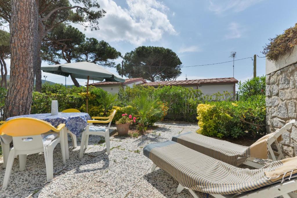 eine Terrasse mit einem Tisch, Stühlen und einem Sonnenschirm in der Unterkunft Villa Fantagali apt 504 in Marina di Campo