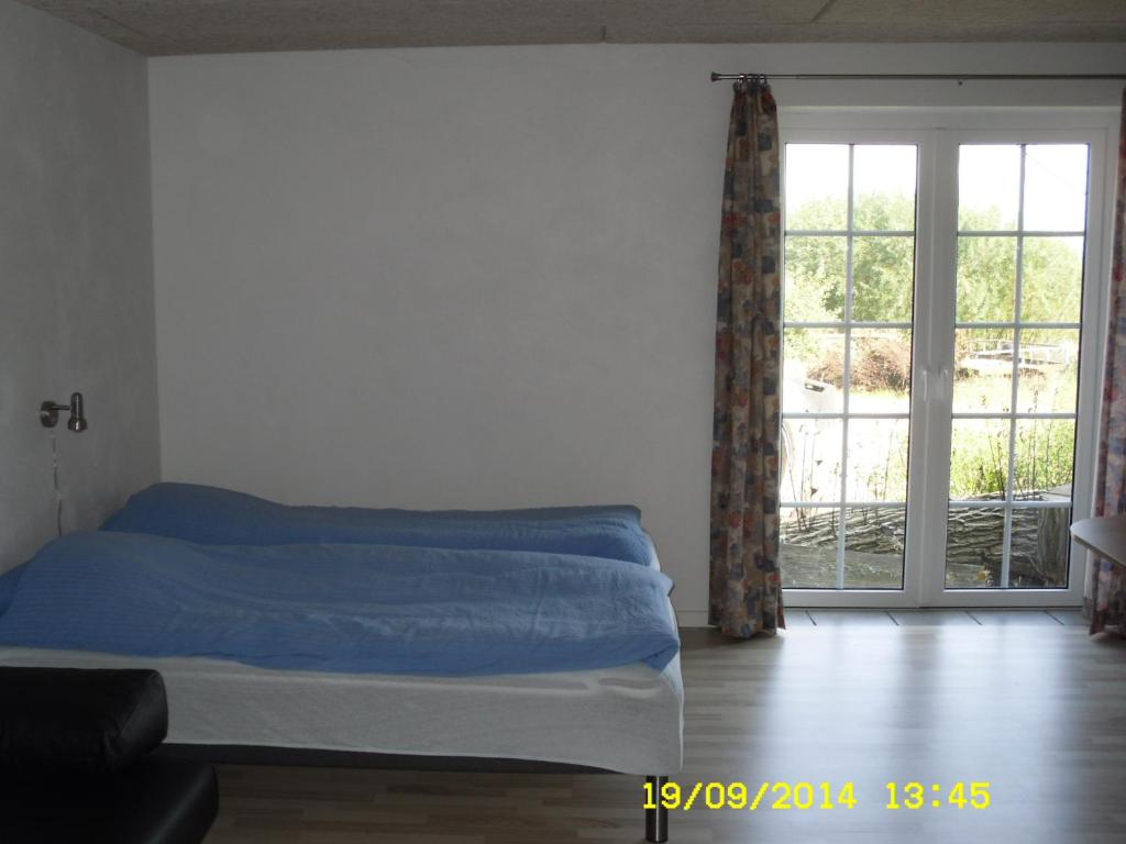 1 dormitorio con cama y ventana grande en Hellesvang, en Guderup