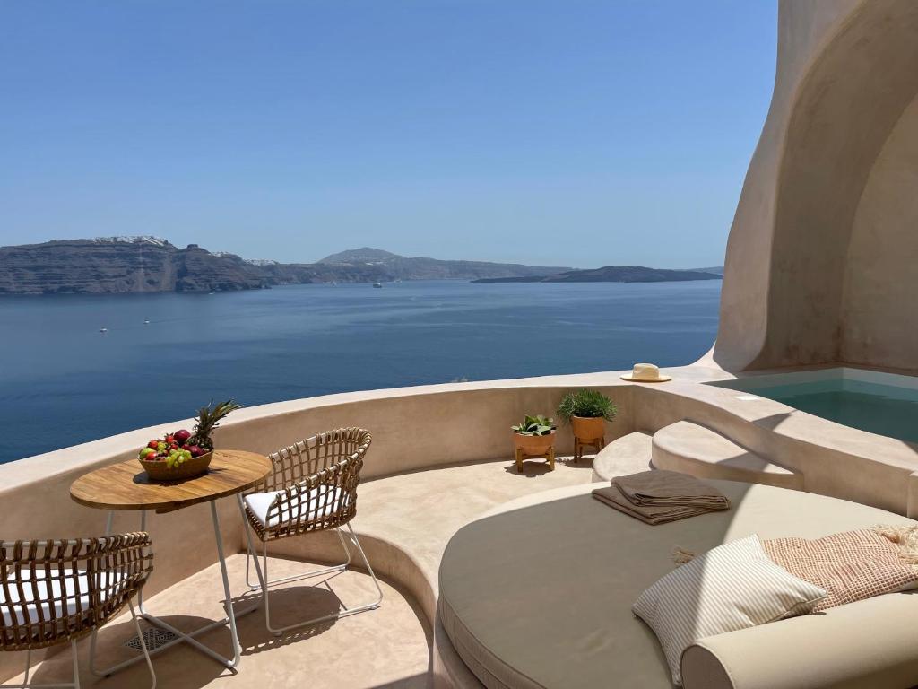 a balcony with a table and chairs and a view of the water at The Exotic Cave Suite in Oia