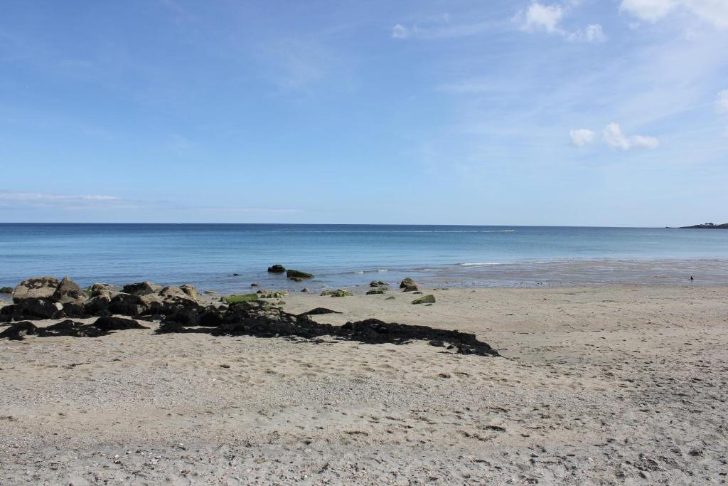 a beach with rocks on the sand and the ocean at Lil' Nauti in Pentewan