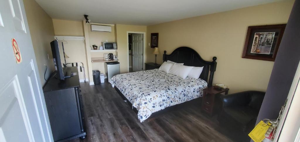 um quarto com uma cama e uma televisão em Fair Isle Motel em Whycocomagh
