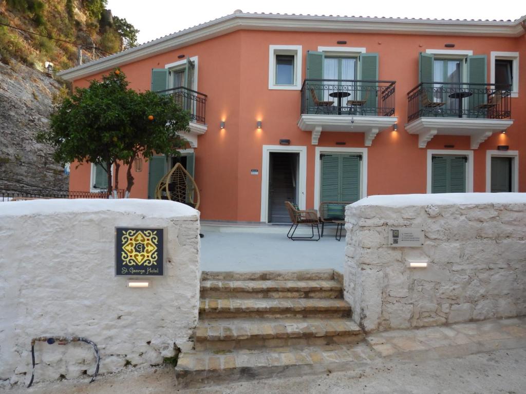 une maison orange avec des escaliers en face de celle-ci dans l'établissement Saint george Hotel Parga, à Parga