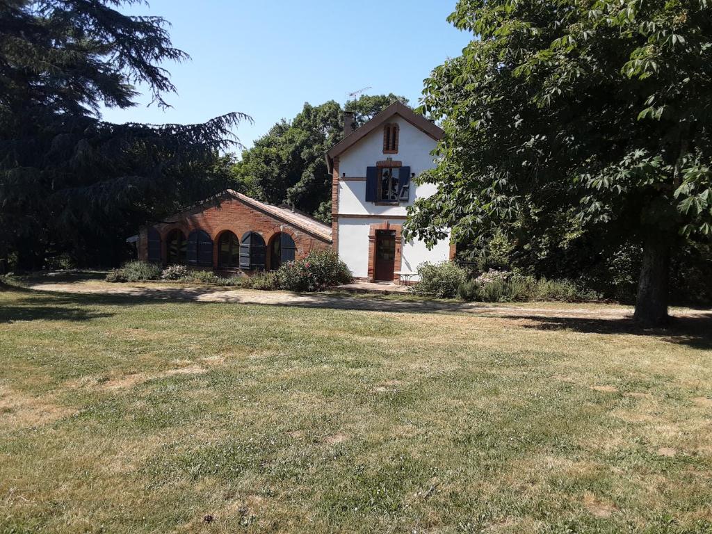 a white house with a tree and a grass field at Le Chais in Villemur-sur-Tarn