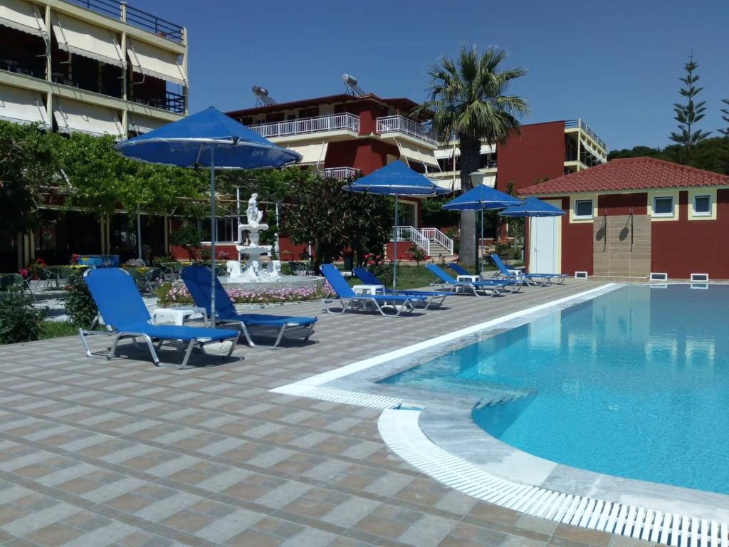 a swimming pool with blue lounge chairs and umbrellas at Brati - Arcoudi Hotel in Arkoudi