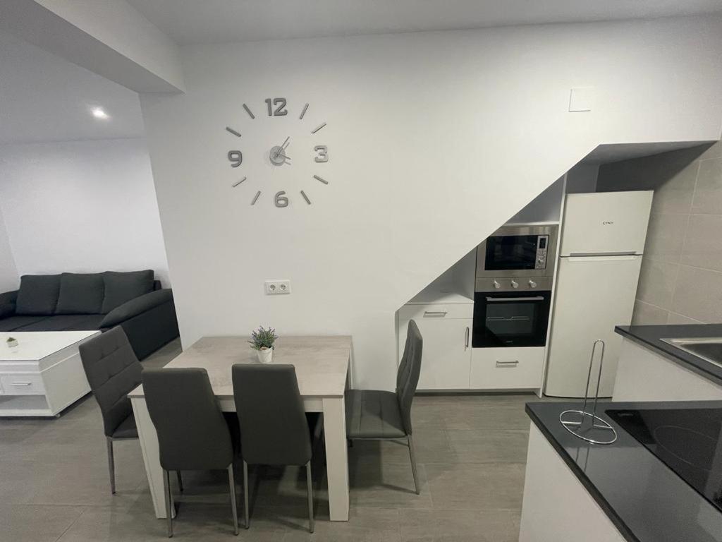 a kitchen with a table and a clock on the wall at Apartamento Conil Playa in Conil de la Frontera