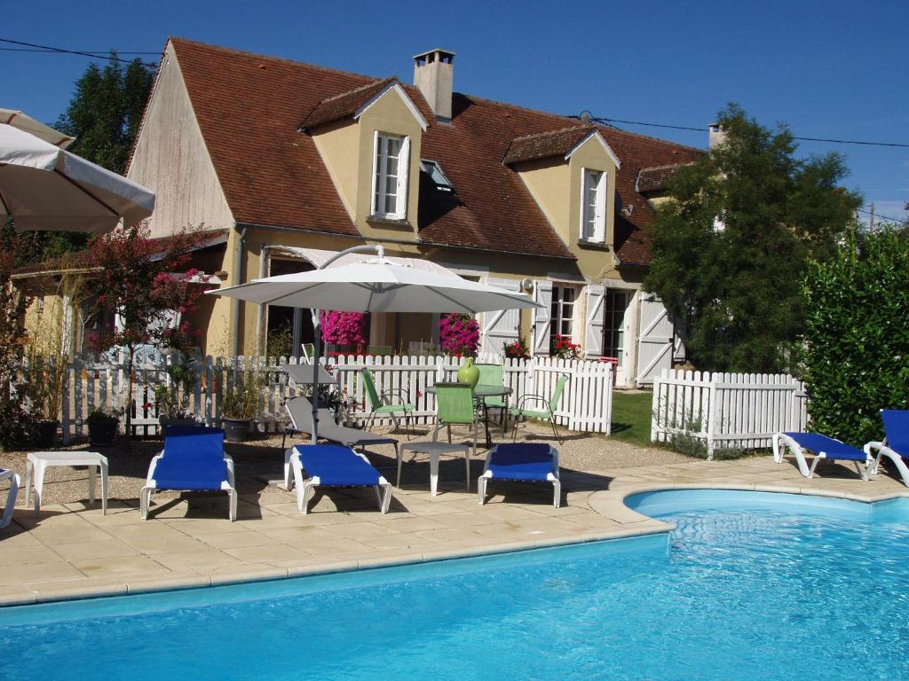 a pool with chairs and an umbrella next to a house at Le Mas de Gramat in Payrac