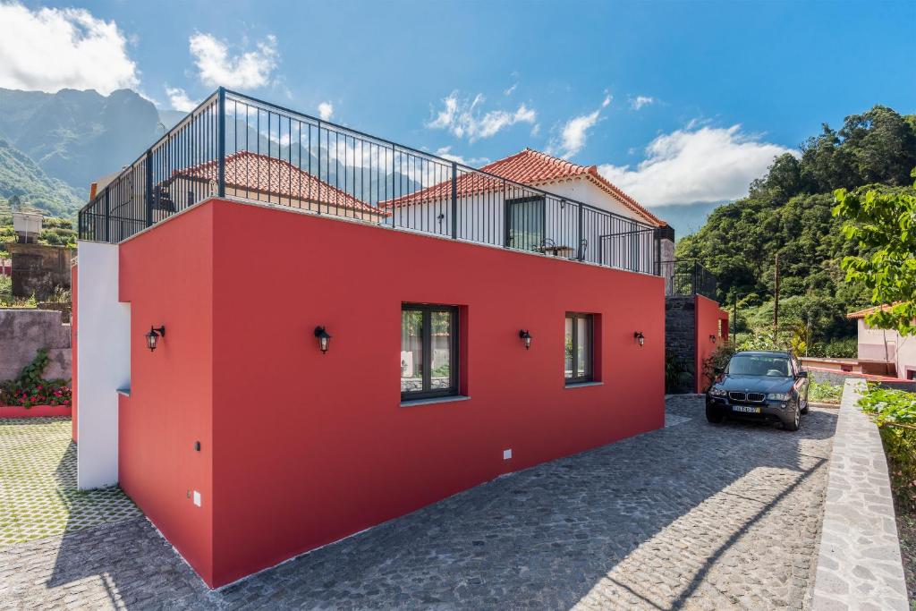 ein rotes Haus mit einem Auto daneben geparkt in der Unterkunft Villa Teresa by Atlantic Holiday in São Vicente