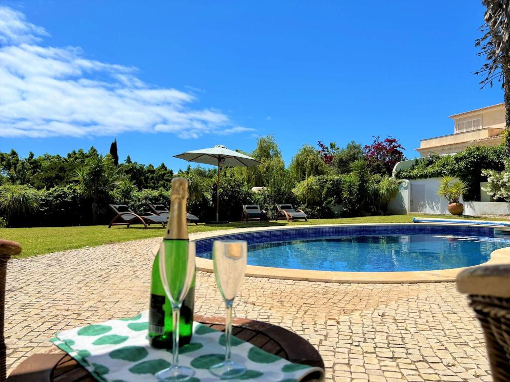 a bottle of champagne and two glasses on a table next to a pool at Albufeira Balaia Villa With Private Pool by Homing in Albufeira