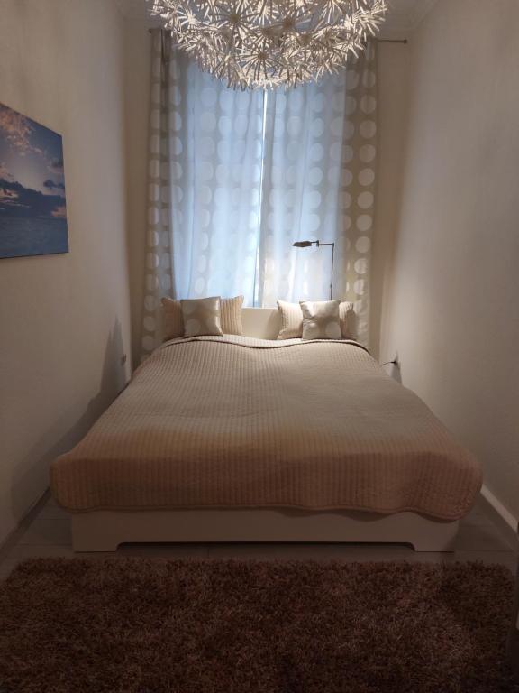 a bedroom with a bed with a chandelier and a window at Gemütliche Zwei-Zimmer-Ferienwohnung "W1" in Zwenkau bei Leipzig im Neuseenland in Zwenkau