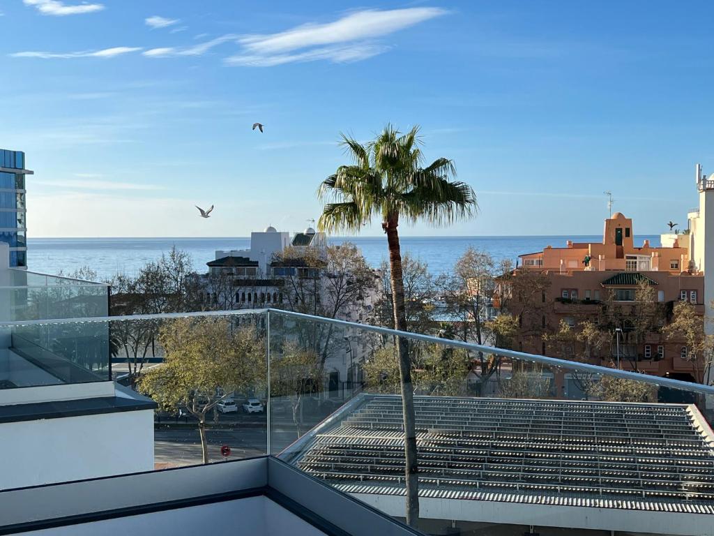 a balcony with a palm tree and the ocean at New build modern ap 4 min walk to the beach and Marbella old town in Marbella