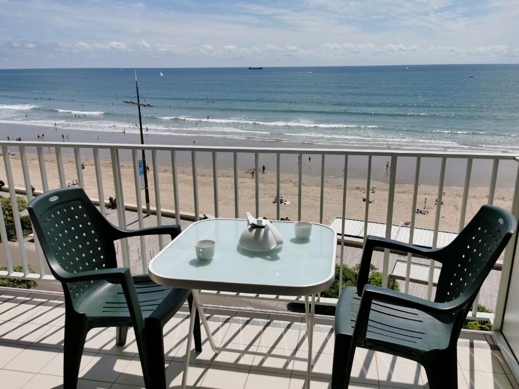 una mesa y sillas en un balcón con vistas a la playa en La Calypsette - Face Grande Plage des Sables d'Olonne, en Les Sables-dʼOlonne