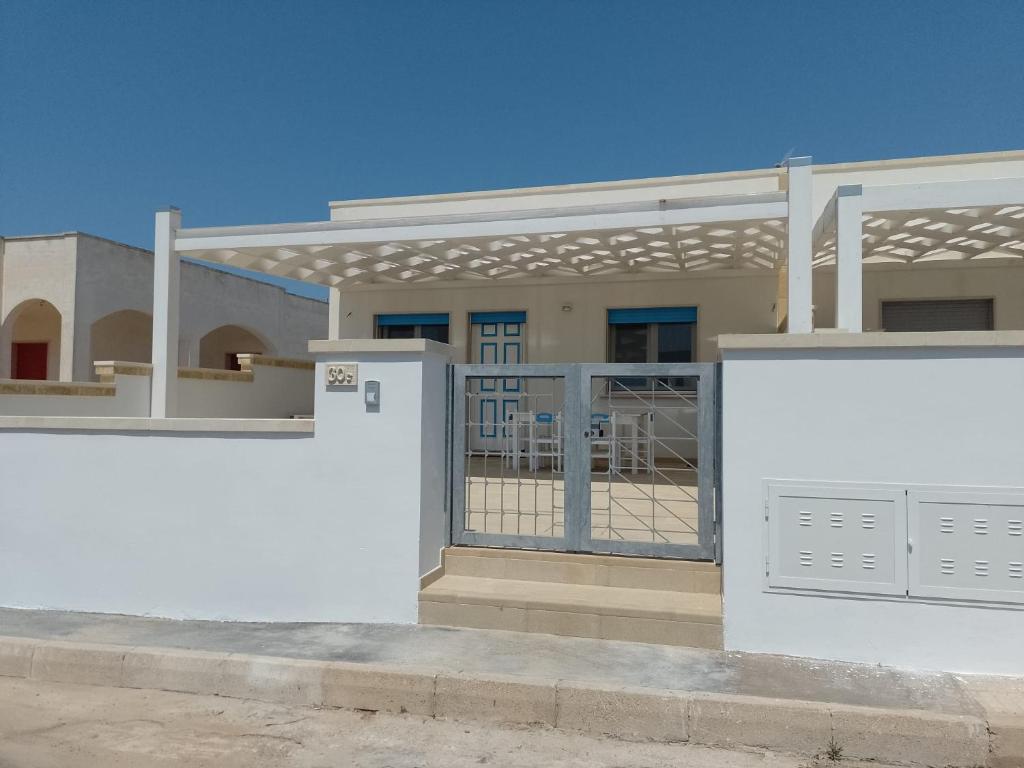 una casa bianca con un cancello e una recinzione di villa,Salentina, marina di Mancaversa a Marina di Mancaversa