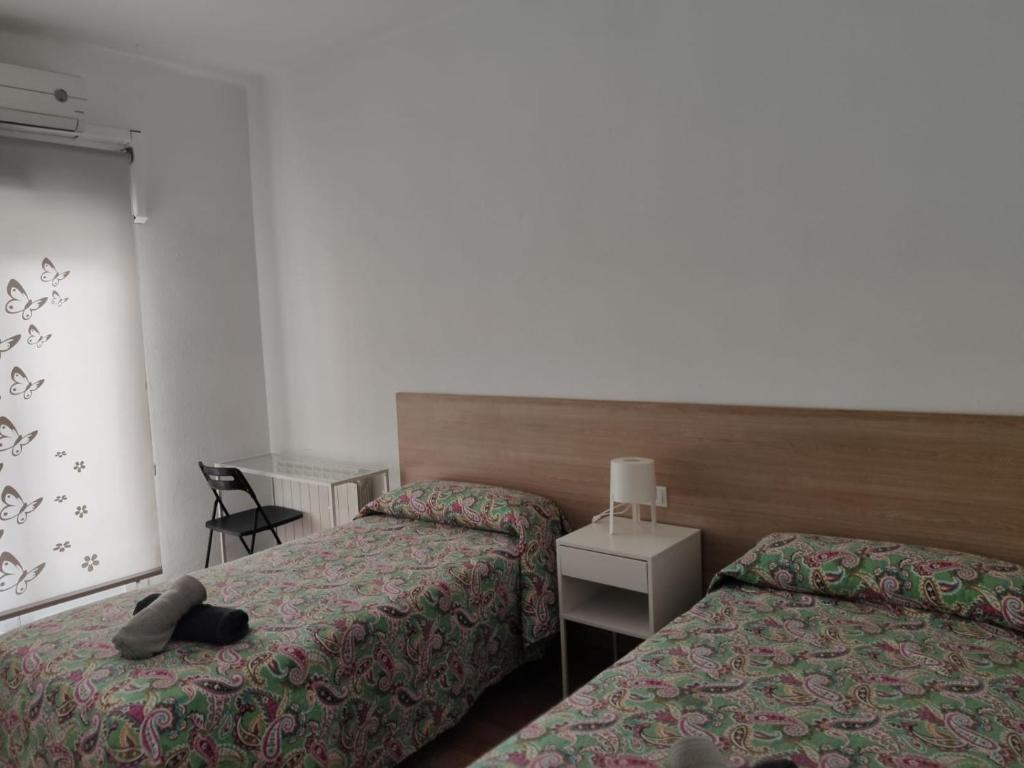 a hotel room with two beds and a chair at Apartamento Como en tu casa in Logroño