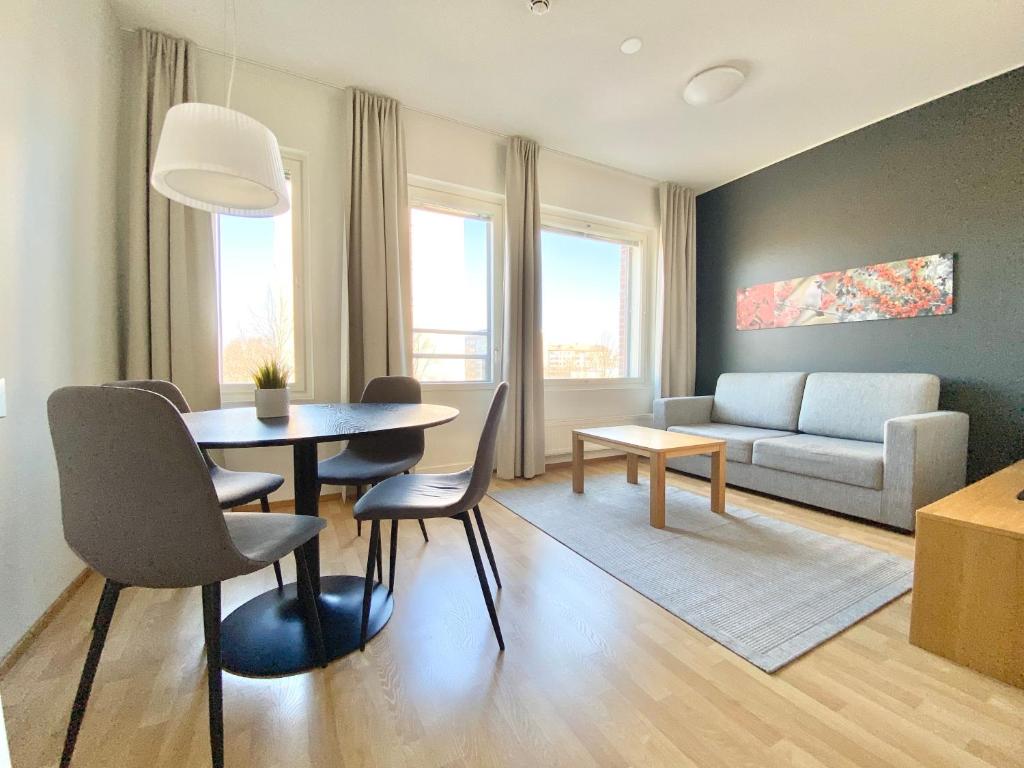 sala de estar con mesa, sillas y sofá en Tammer Huoneistot - City Suite 3 - Public Sauna, Gym & Pool en Tampere