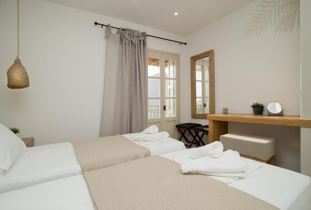 two white beds in a room with a desk at Horizon Hotel Kalymnos in Myrties