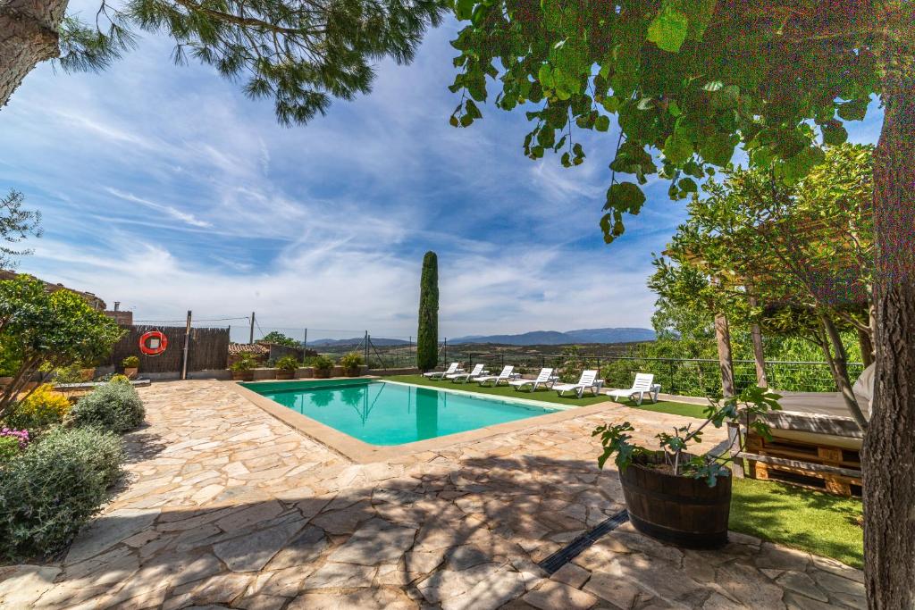 una piscina en un patio con sillas y árboles en Cal París Rural, 