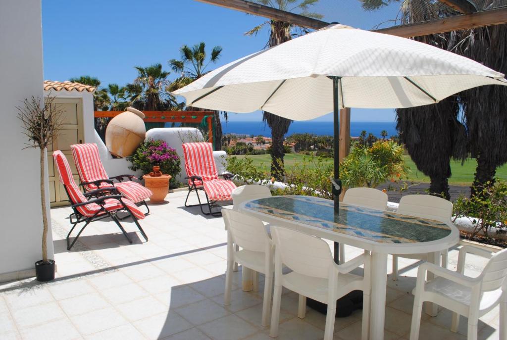 un patio con mesa, sillas y sombrilla en Bella Vista, Golf del Sur, en San Miguel de Abona