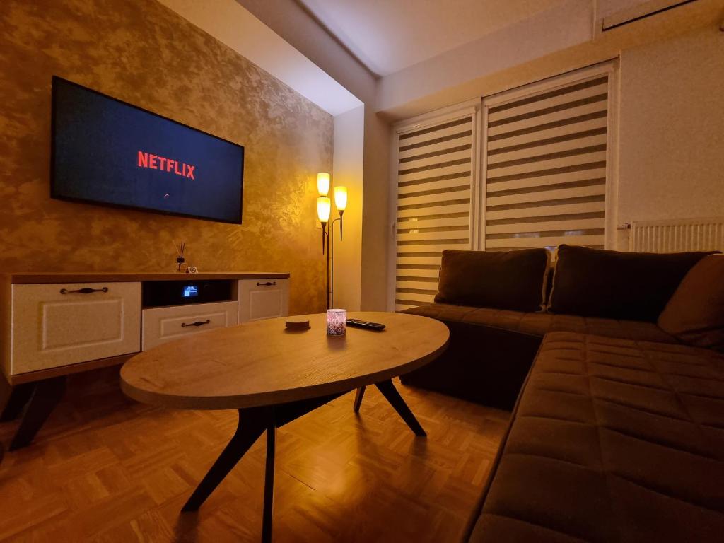 ein Wohnzimmer mit einem Tisch und einem TV an der Wand in der Unterkunft Cozy & Quiet Apartment Ohrid in Ohrid