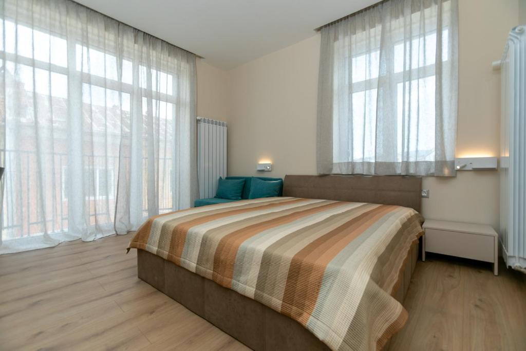 1 dormitorio con 1 cama grande y ventanas grandes en Луксозни студия “Старият Батак” / Luxury studios “The Old Batak” en Batak