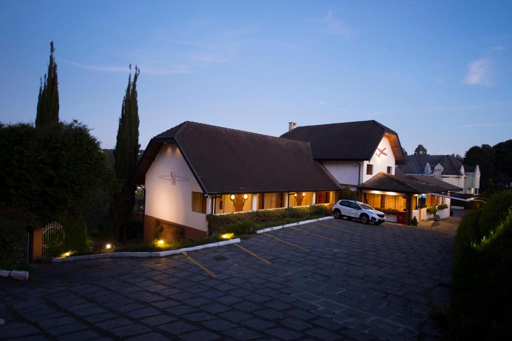 una casa con un coche aparcado en una entrada en Pousada Constellation Lodge, en Campos do Jordão