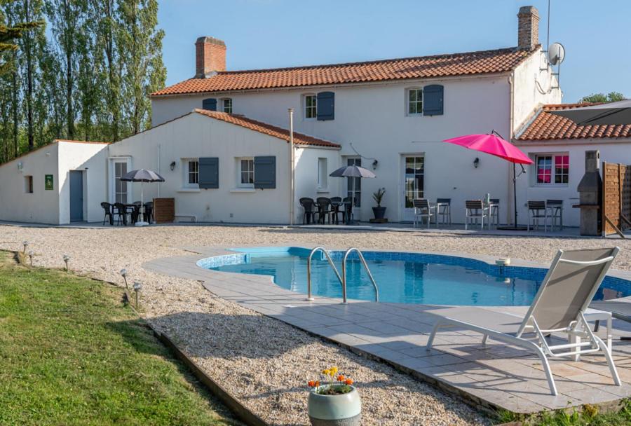 Villa con piscina frente a una casa en Gîtes Le Bois Berranger, en Saint-Urbain