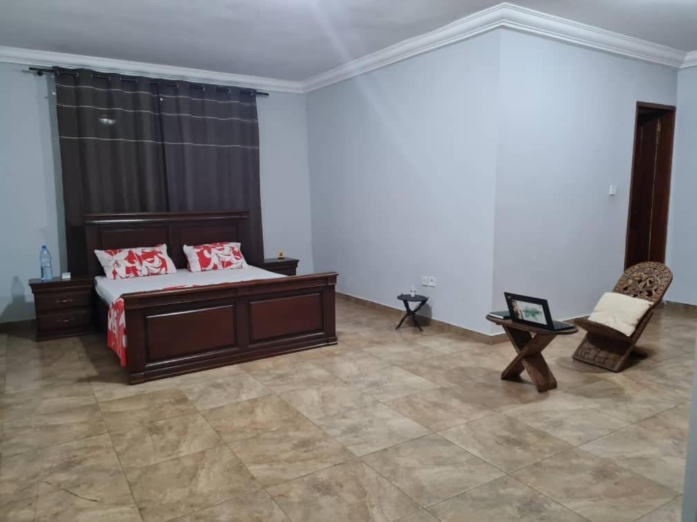 - une chambre avec un lit et une chaise dans l'établissement KARIBU G&H Location Meublée Furnished Rental, à Yaoundé