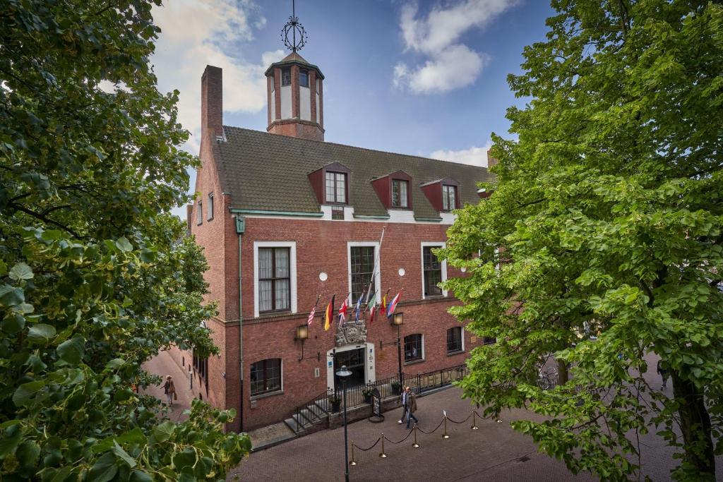 a large red brick building with a clock tower at Boutique Hotel The Roosevelt in Middelburg