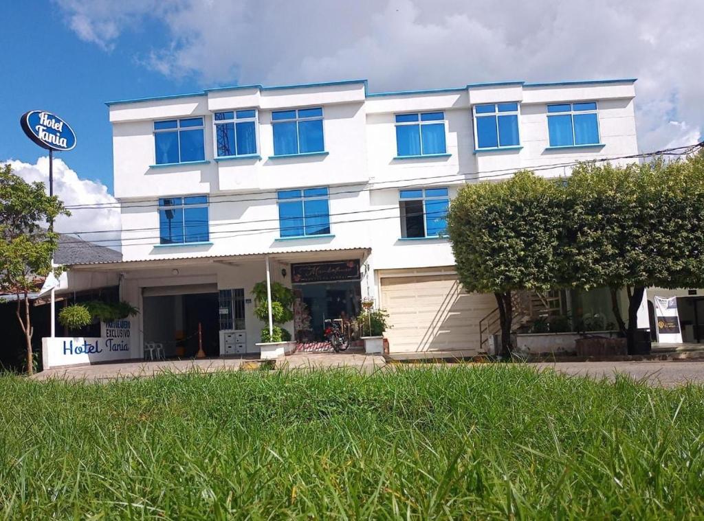 a white building with blue windows on a street at HOTEL TANIA in Caucasia